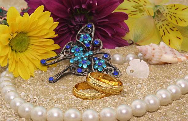 Sea Shells With Flowers and Wedding Rings on Sand