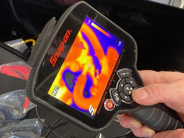 A technician holding a thermal imaging tool for auto-diagnostics