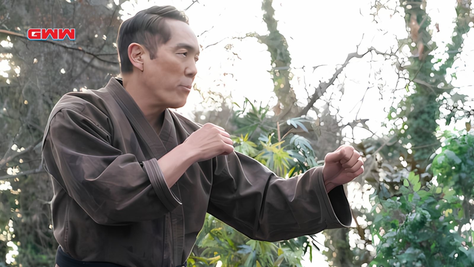 Chozen in martial arts attire posing outdoors, surrounded by greenery.