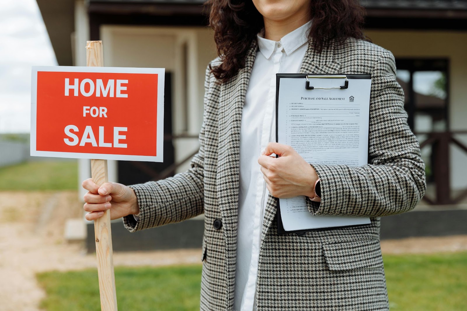Agente inmobiliaria sosteniendo un cartel de "Home for Sale" y un contrato