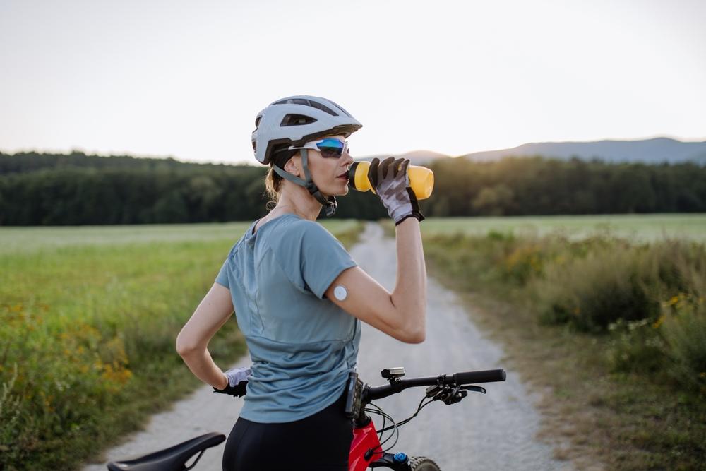 woman on bike wearing a continuous glucose monitor on her upper arm