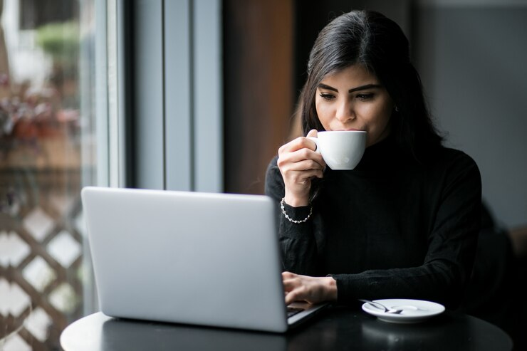 Woman with a teacup looking at her laptop