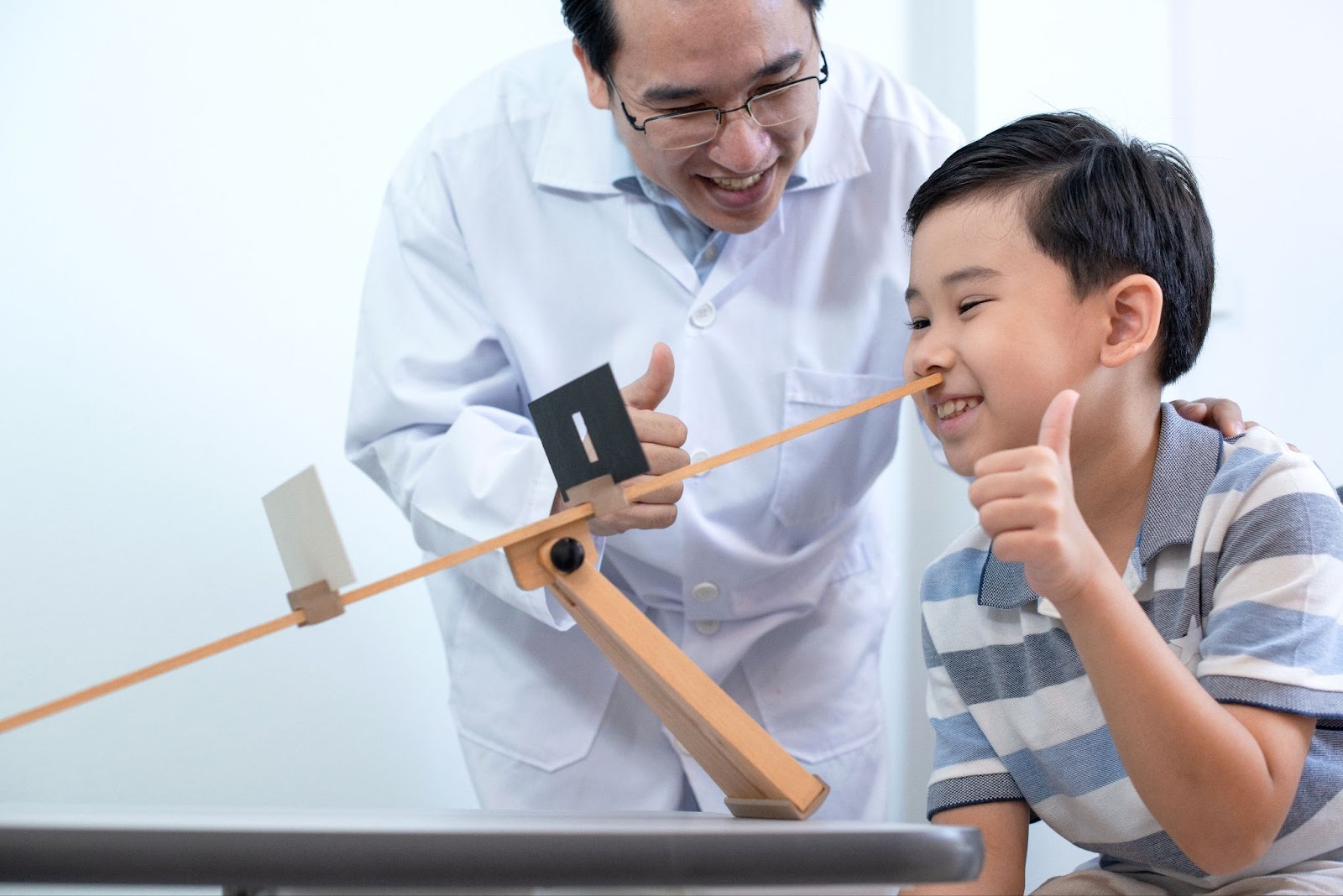 A smiling optometrist and a young boy giving a thumbs-up during vision therapy