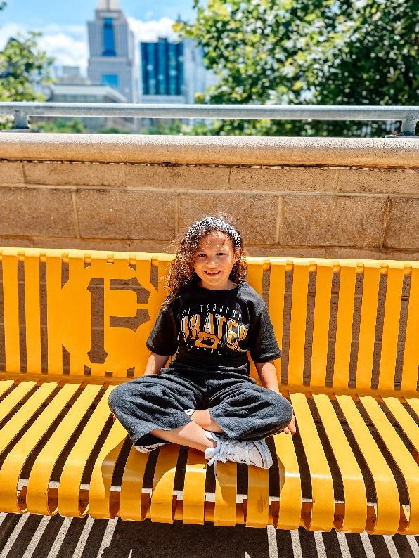 A child sitting on a yellow benchDescription automatically generated