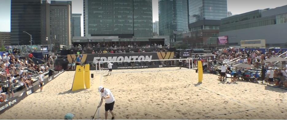 Beach volleyball court in downtown Edmonton with a crowd gathering in the stands on 3 sides.