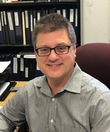 A person sitting in front of a shelf of binders

Description automatically generated with low confidence