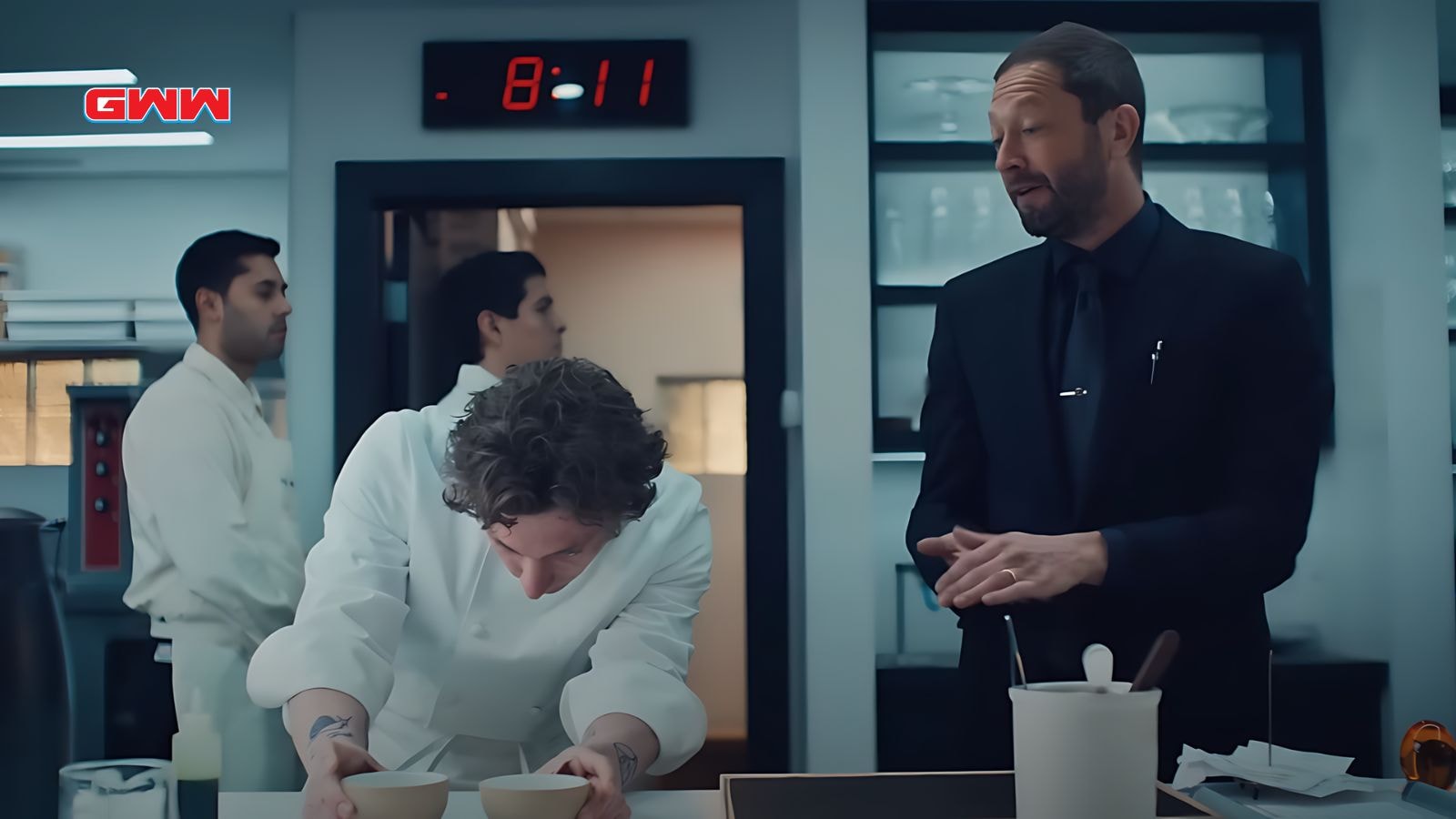 Carmy intensely focuses on plating food in a busy kitchen.