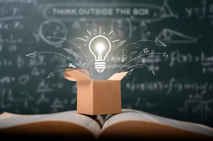 Hand-drawn light bulb coming out of a box in front of a blackboard