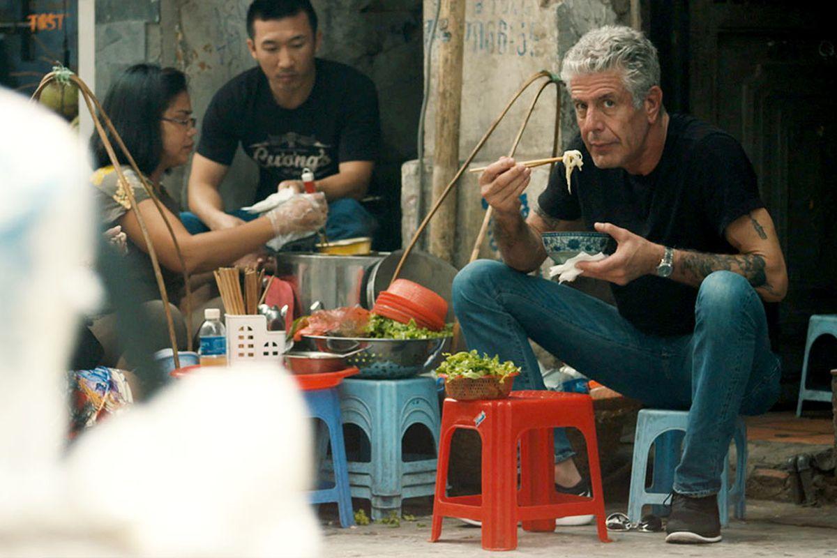 A person eating noodles with his hands

Description automatically generated