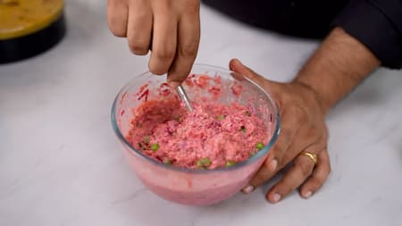 Mixing grated beetroot, carrot, and oats powder to make batter.