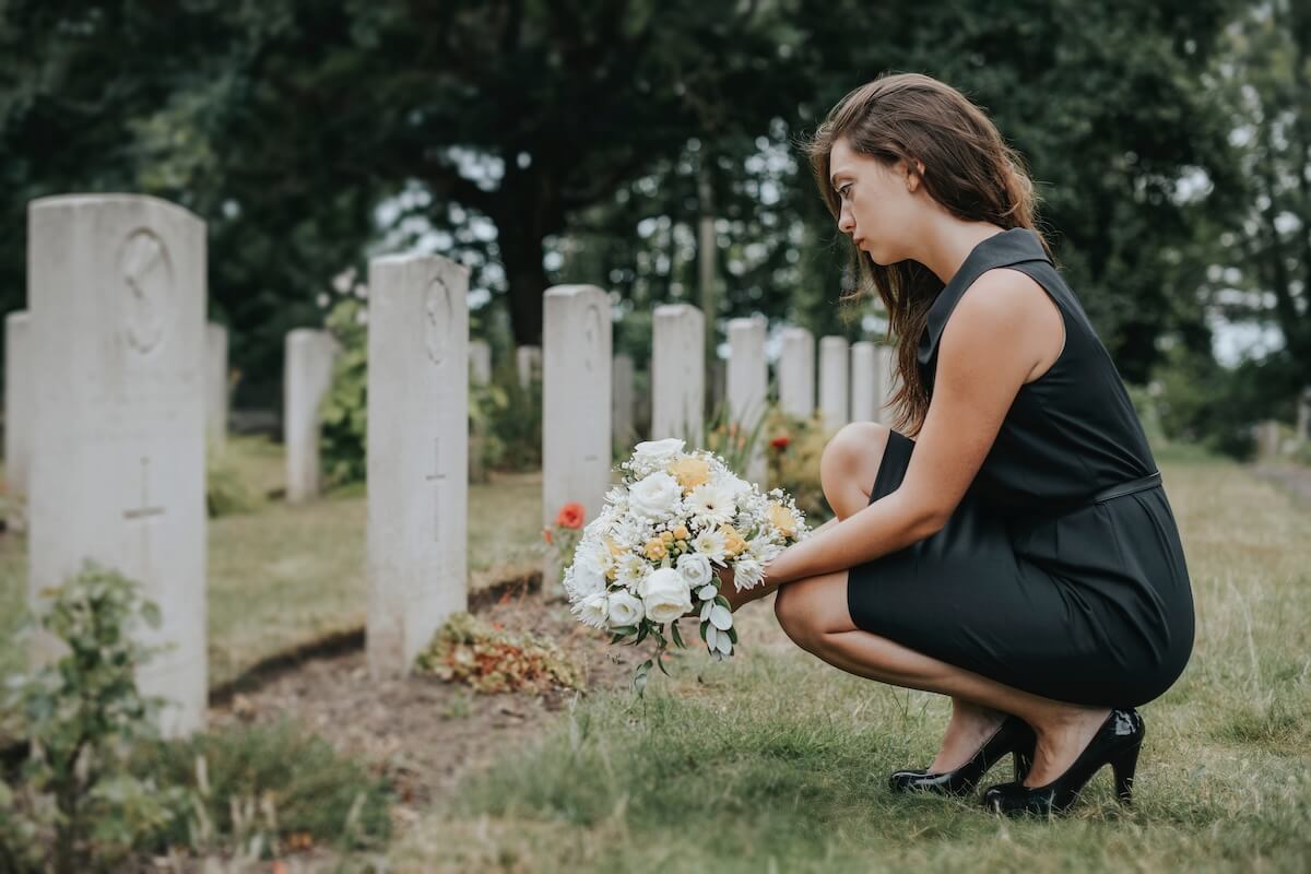 Bereavement leave: woman laying flowers on a grave