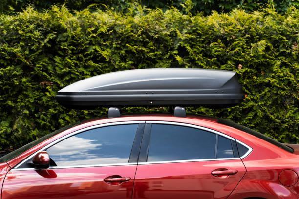 Trunk installed on roof of red sedan car. Equipment for travel. Concept of storage, transportation Trunk installed on roof of red sedan car. Equipment for travel. Concept of storage, transportation R1S Roof Rack stock pictures, royalty-free photos & images