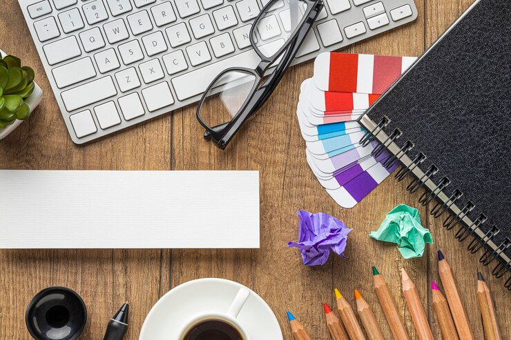 Top view of items on a table like keyboard, glasses, and paint cards