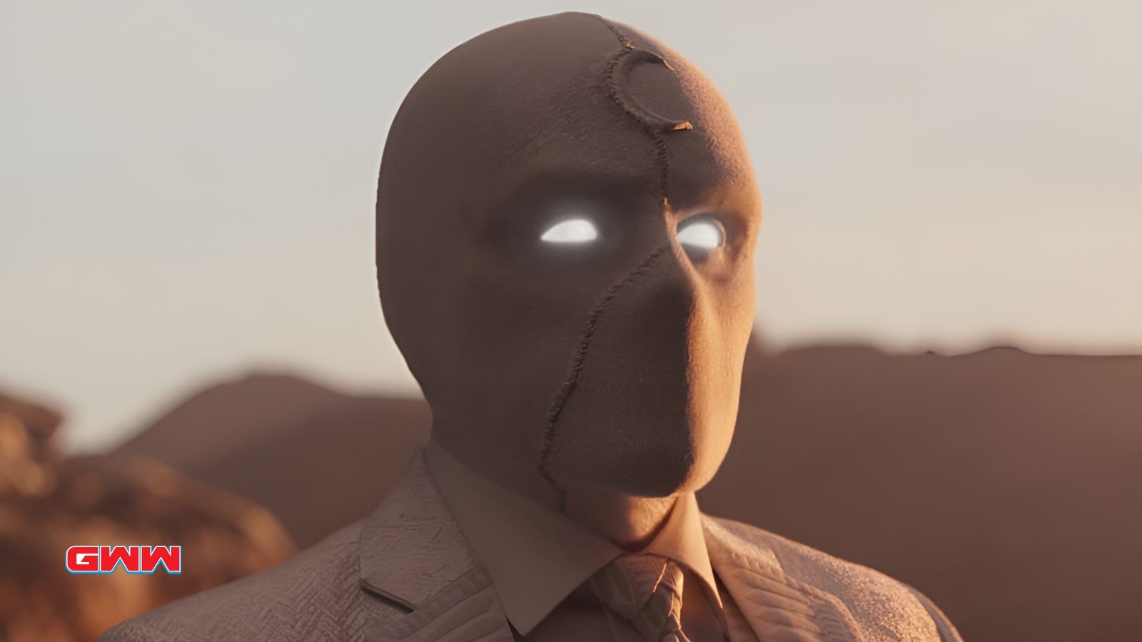 Close-up of Moon Knight with glowing eyes and a desert background.
