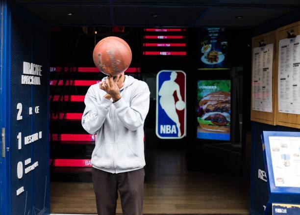 NBA Café Barcelona in Barcelona. Fit man spinning a basketball. Barcelona, Spain - February 20, 2019: The first official restaurant of the NBA in Europe in the epicenter of the city of Barcelona, in Las Ramblas, 120. Located on three floors of a spectacular and historic neoclassical building overlooking the Ramblas, in a unique area of the city, to be able to live and enjoy an authentic NBA experience. A menu based on the best recipes of American cuisine, with oriental and Mexican influences, quality products and delicious sauces. nba  stock pictures, royalty-free photos & images