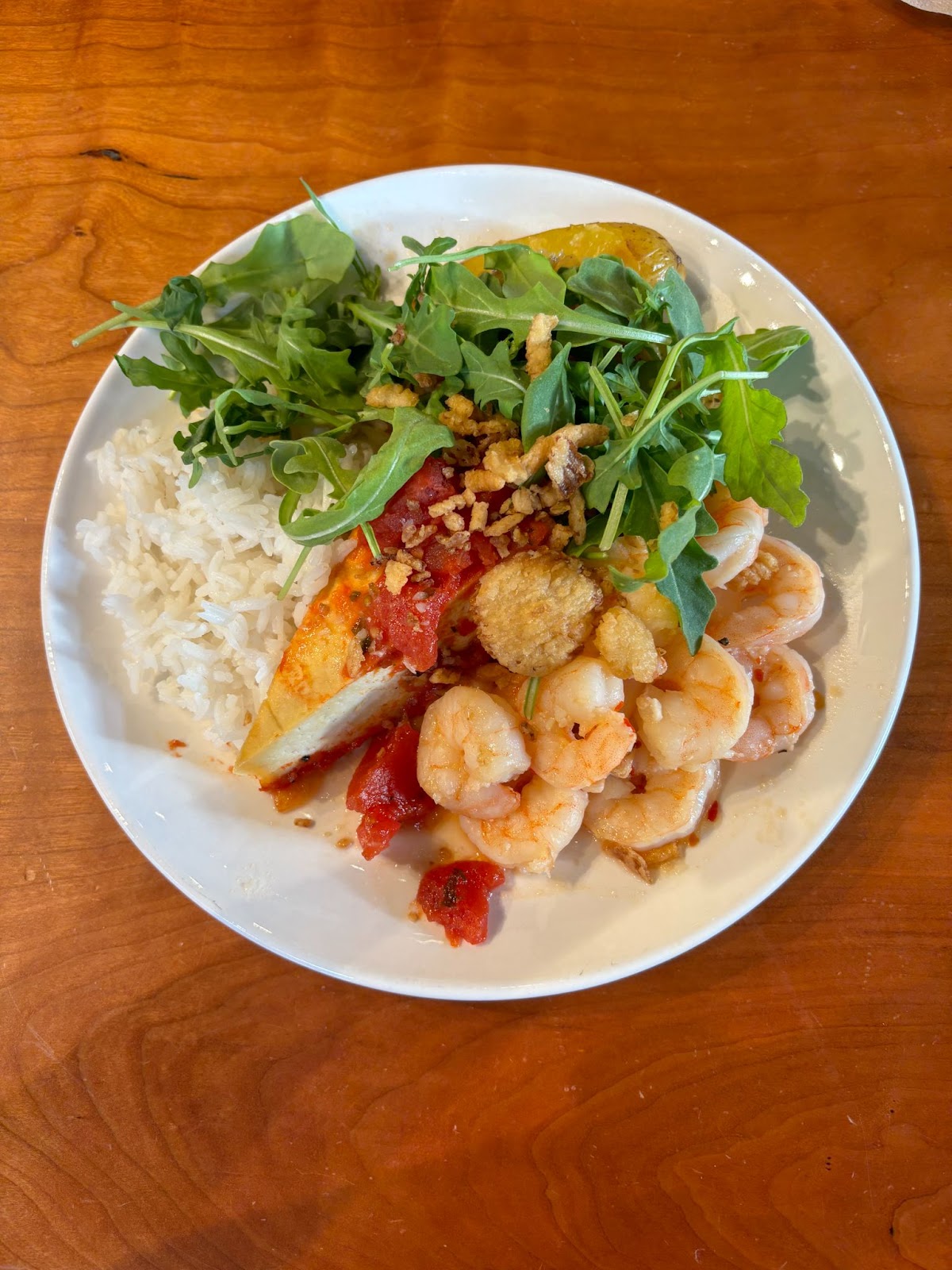 A plate of food with rice, arugula, tofu, and shrimp