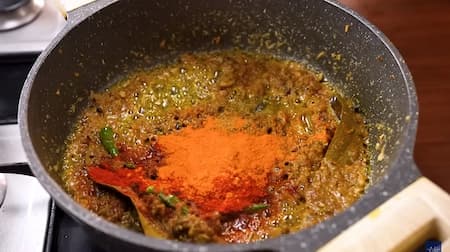 Masala mixture in a pan with creamy curd being stirred in, along with fresh coriander leaves and kasoori methi, adding a smooth and aromatic touch.