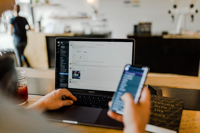 A person using mobile phone and laptop to engage in bigger digital community.