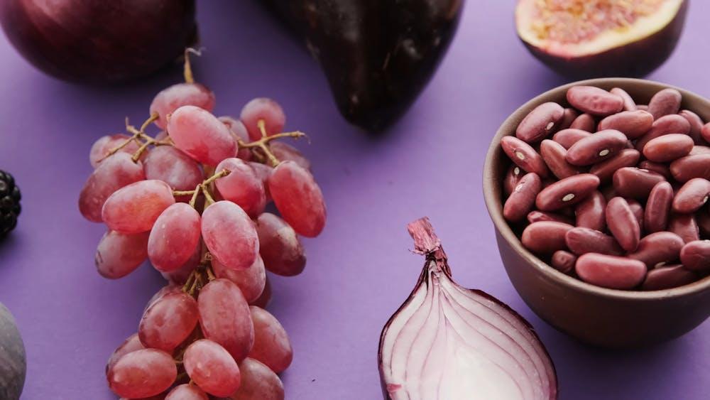 A bowl of red grapes and a onion

Description automatically generated