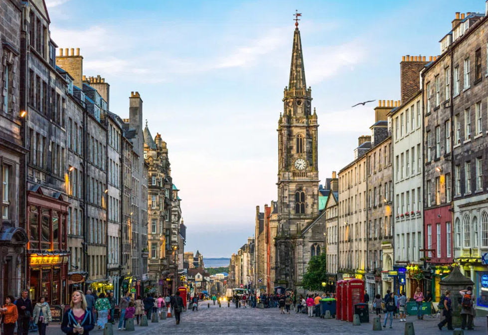 A street with a clock tower and people walking on it

Description automatically generated