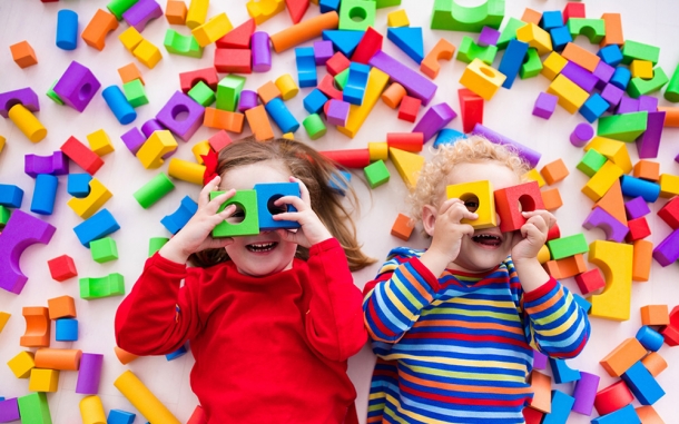 Two children laying in a pile of blocks 