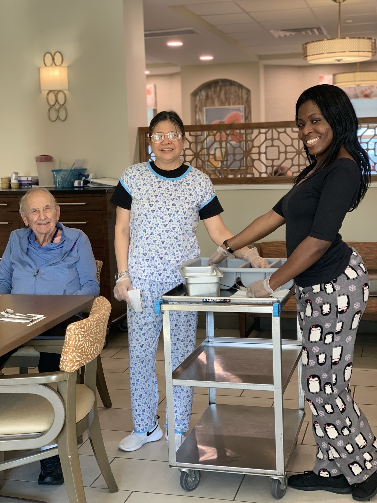 A senior and group of subacute rehab workers smiling at the camera in a cafeteria