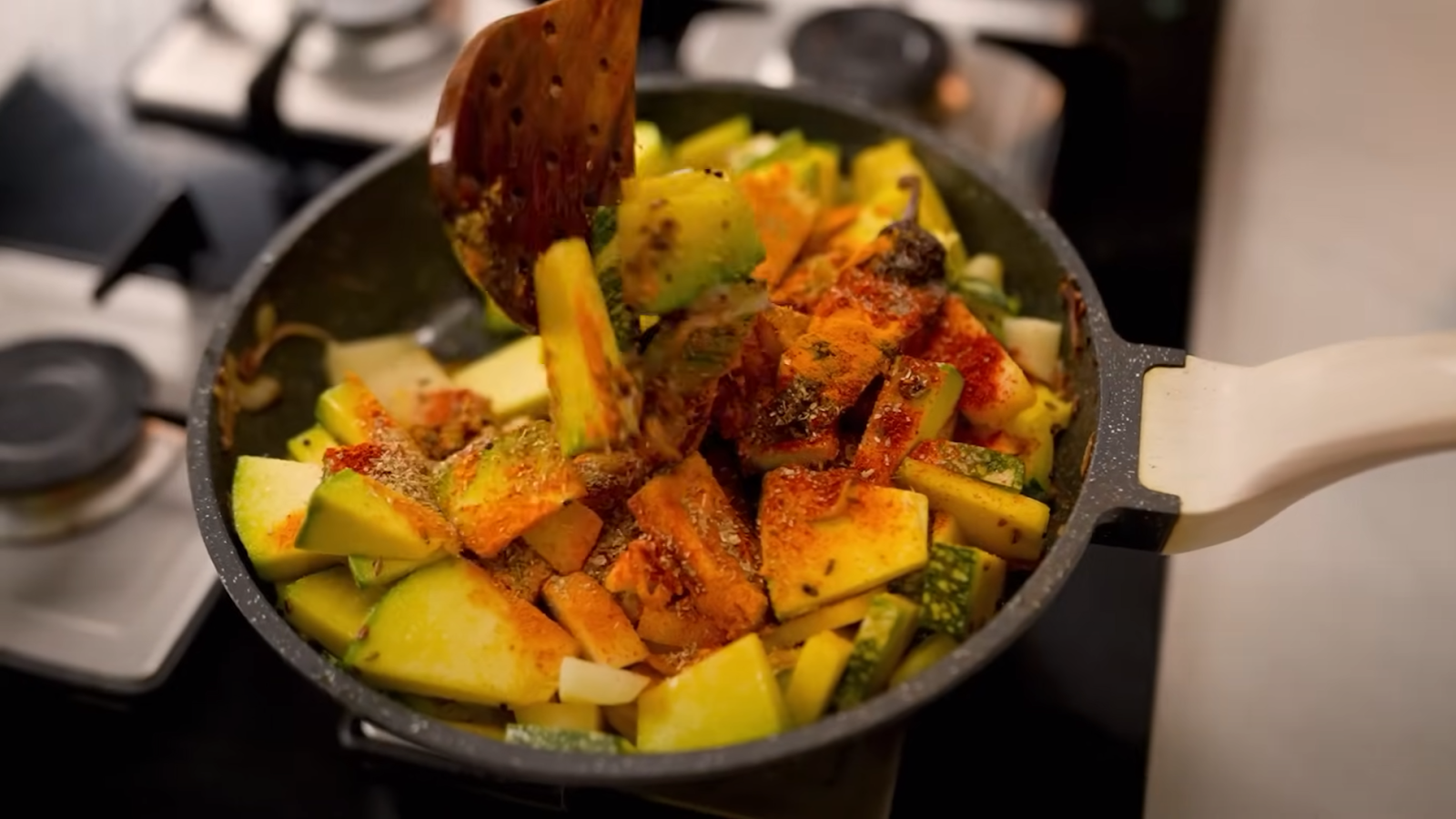 Adding sliced pumpkin and potatoes to a pan with aromatic spices.