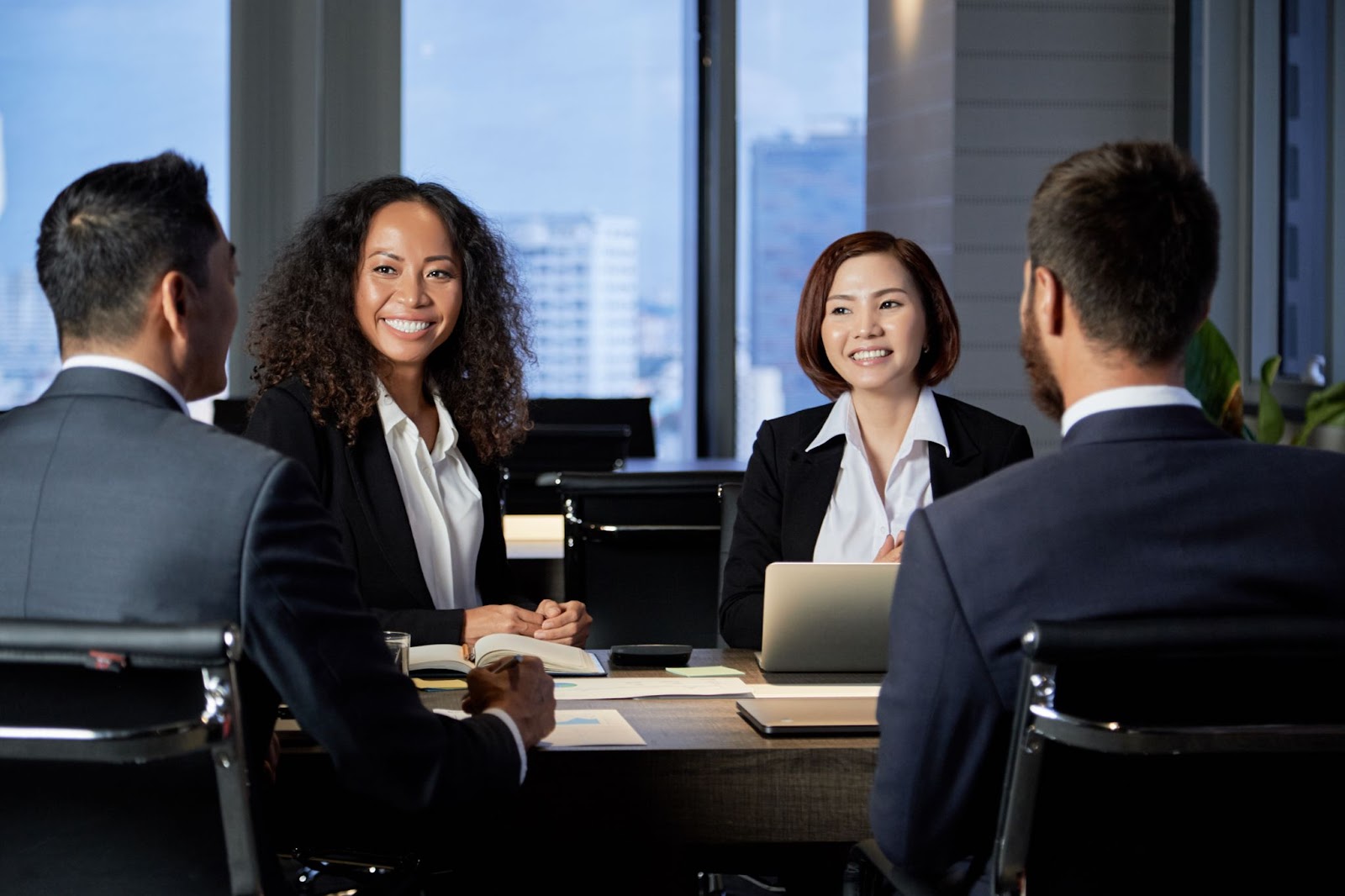 Four consultants discuss strategy in a boardroom. 