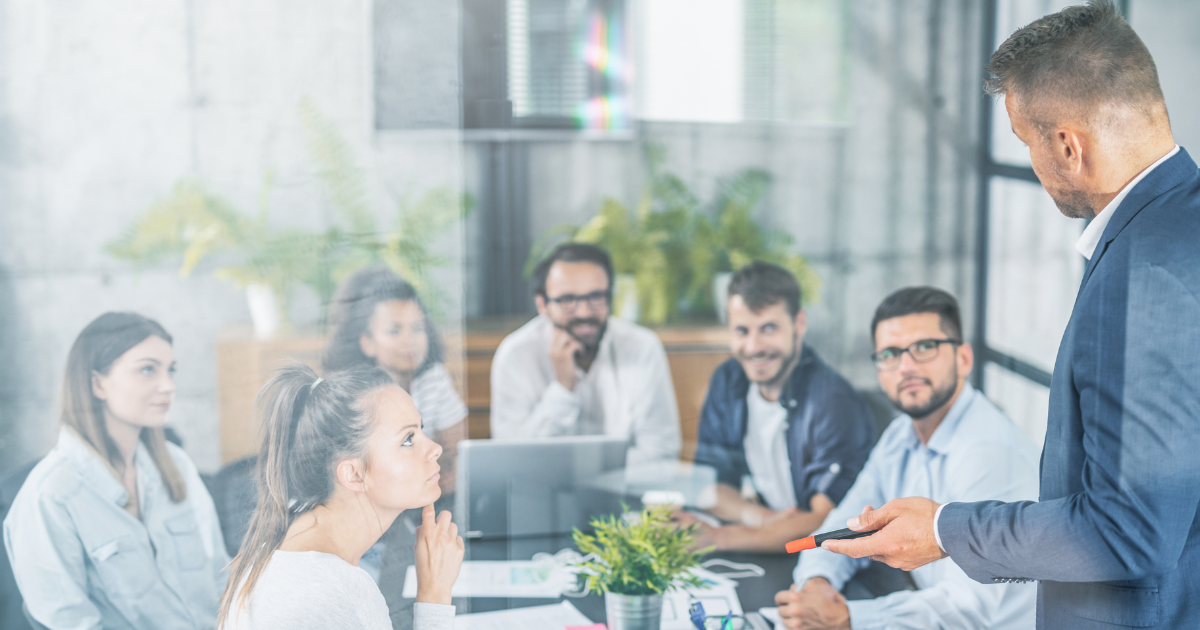 A group of people participating in an Enterprise Agile Coaching session, seated in a circle with a facilitator taking notes.