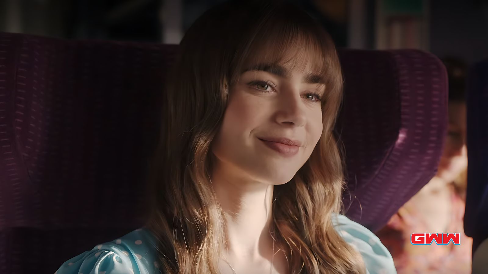 Emily smiling while sitting on a train with a purple seat.