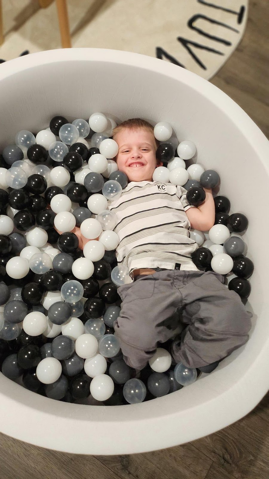 A child lying in a tub of ballsDescription automatically generated