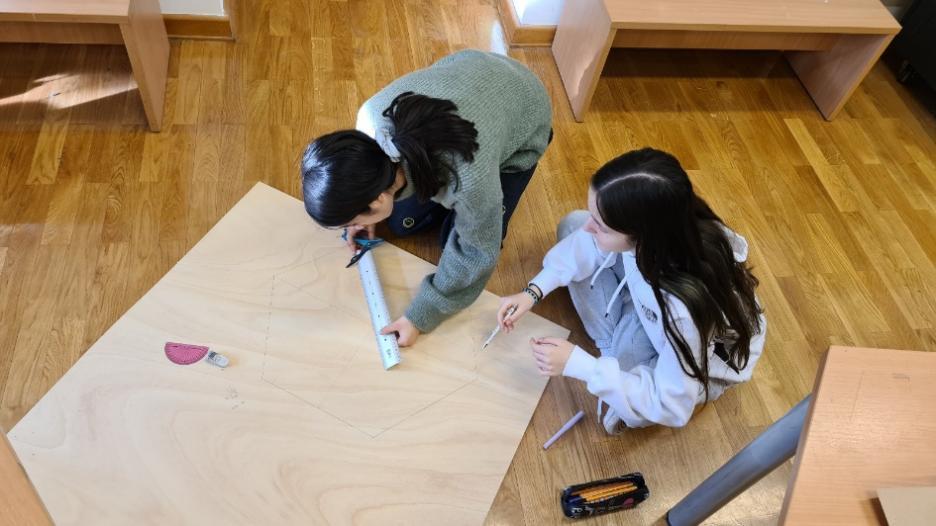 A couple of kids working on a wood table

Description automatically generated