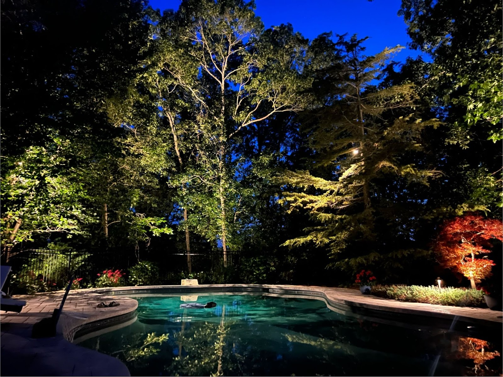 a stunning pool area at night, with landscape lighting in Winchester, MA