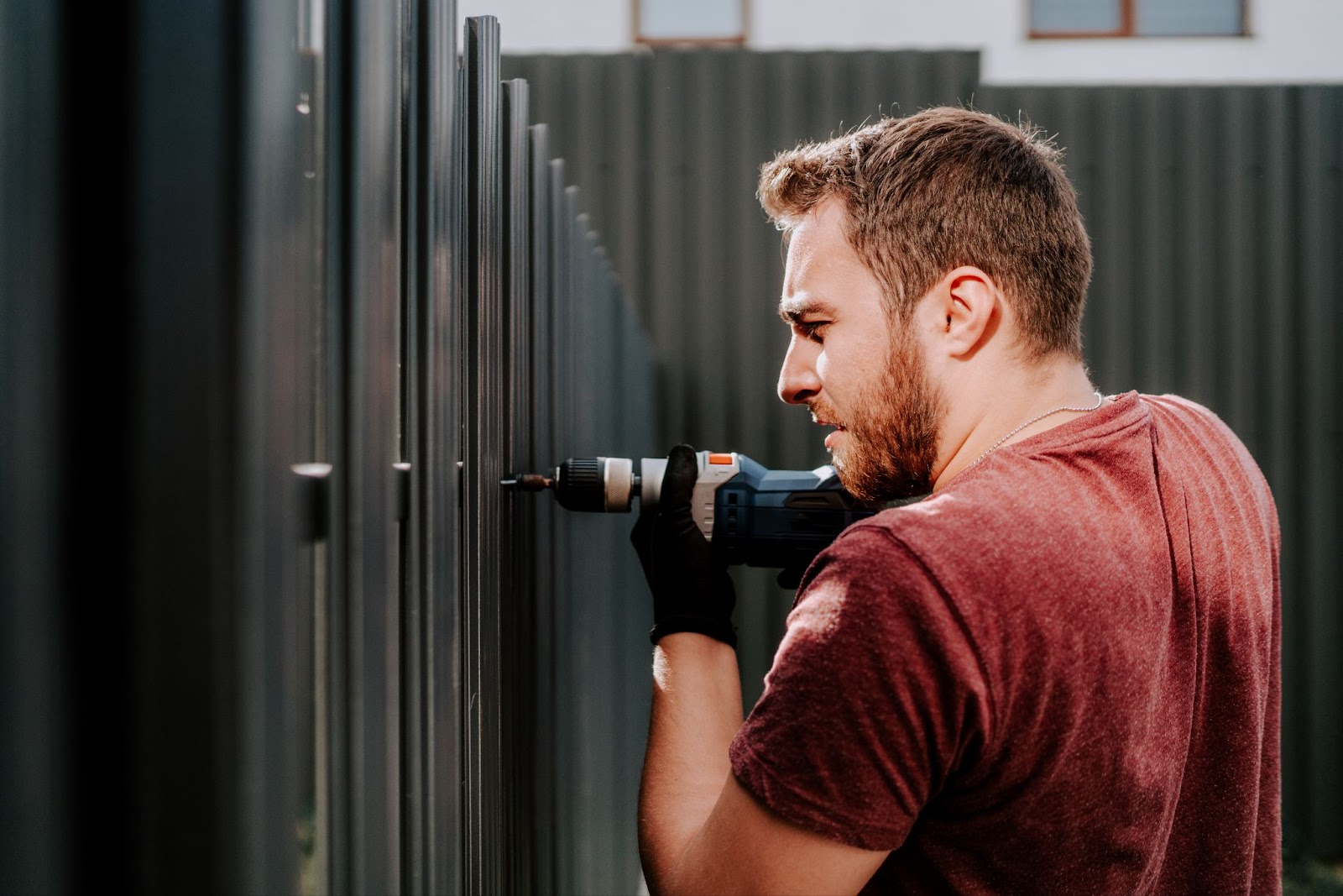 A male worker installs the gate fences with an electric screwdriver. 