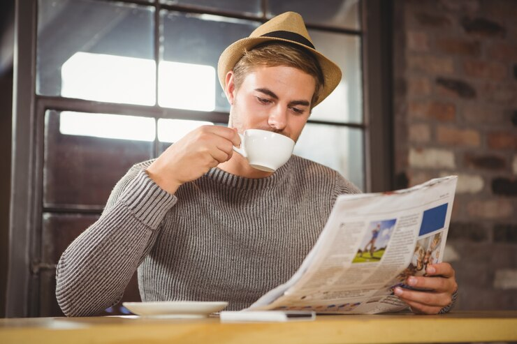 Man reading the newspaper and drinking coffee