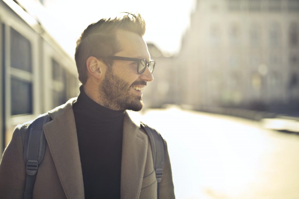 businessman walking down a street looking happy 