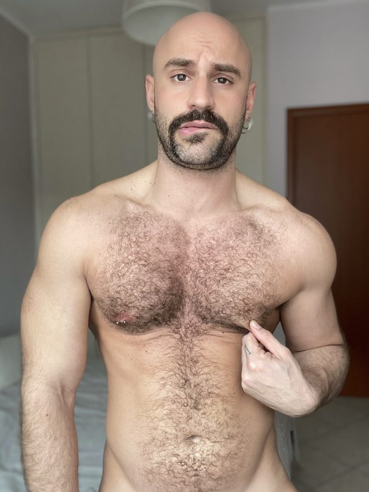 Mister Caccamo pinching his left nipple while biting his lip naked while taking an iphone selfie