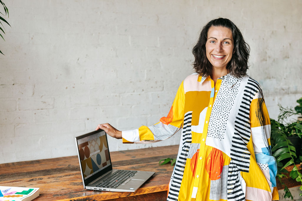 Copywriter Nadine Nethery smiles next to her laptop.