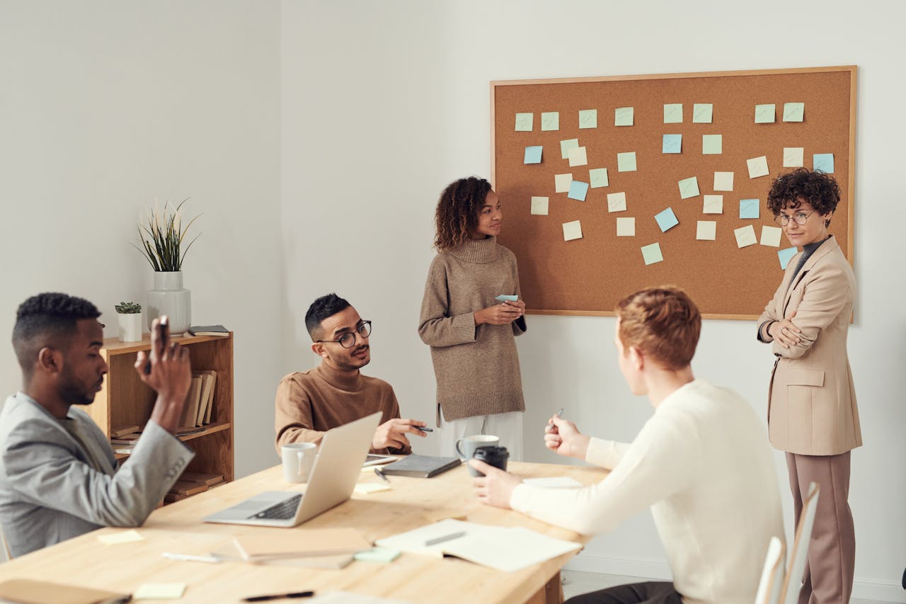 Group of professionals in a meeting room, brainstorming ideas with colorful sticky notes on a whiteboard.