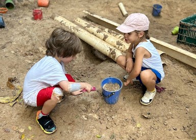 Imagem mostra duas crianças brincando na areia.