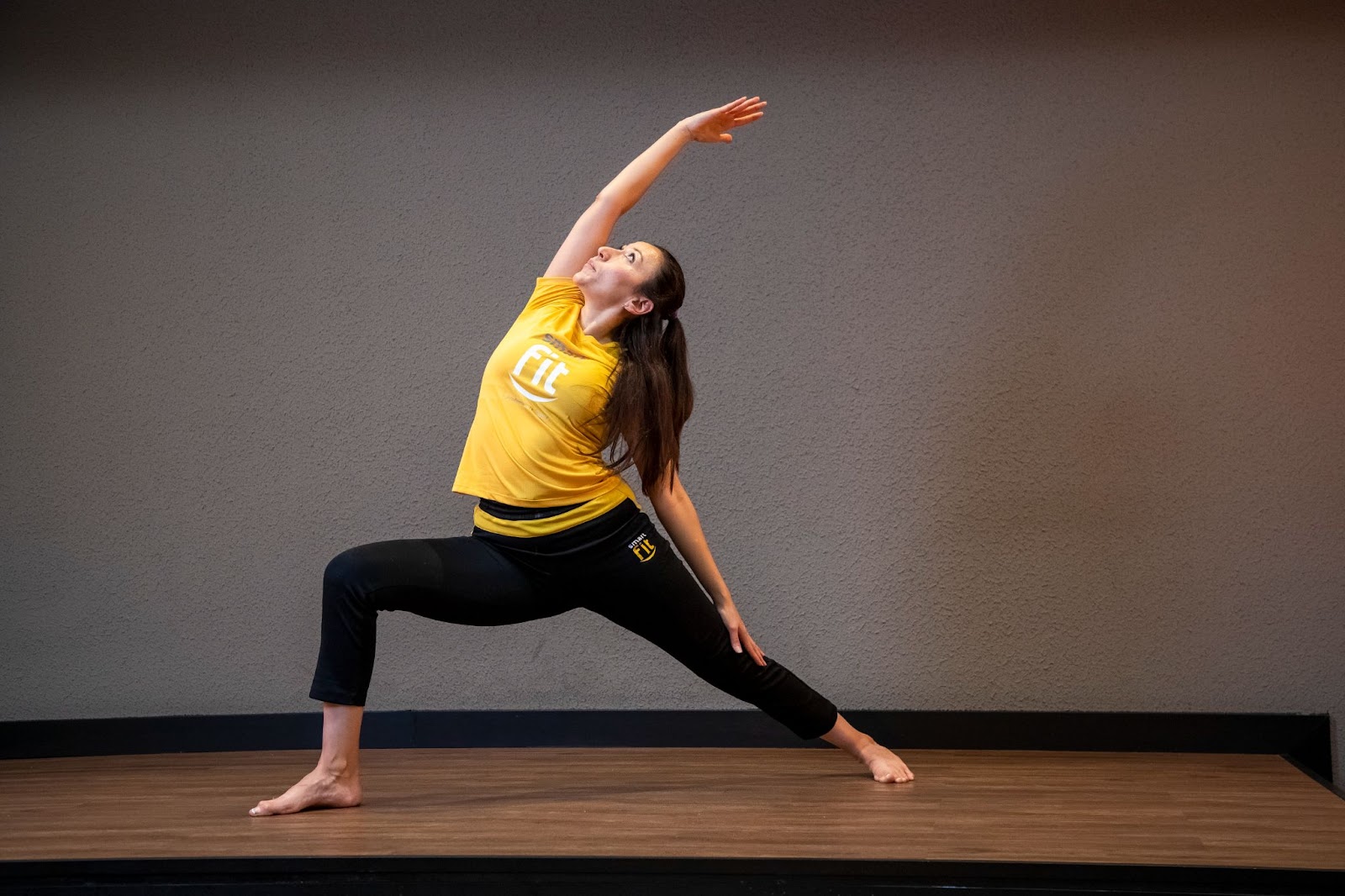 mujer con uniforme de profesora de un gimnasio Smart Fit, realizando una posicion de yoga