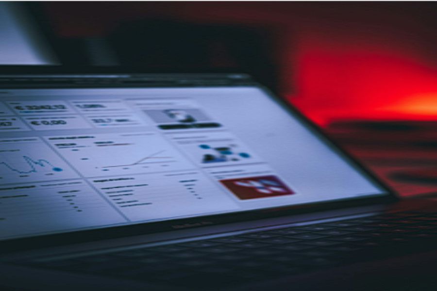 Laptop screen displaying analytics dashboard with graphs and metrics in dim lighting.