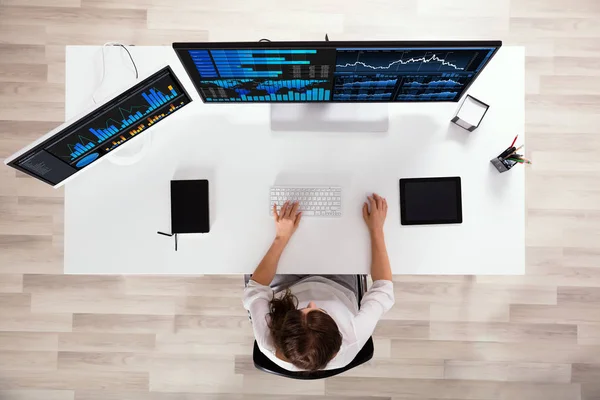 A woman working on the work desk with dual monitors