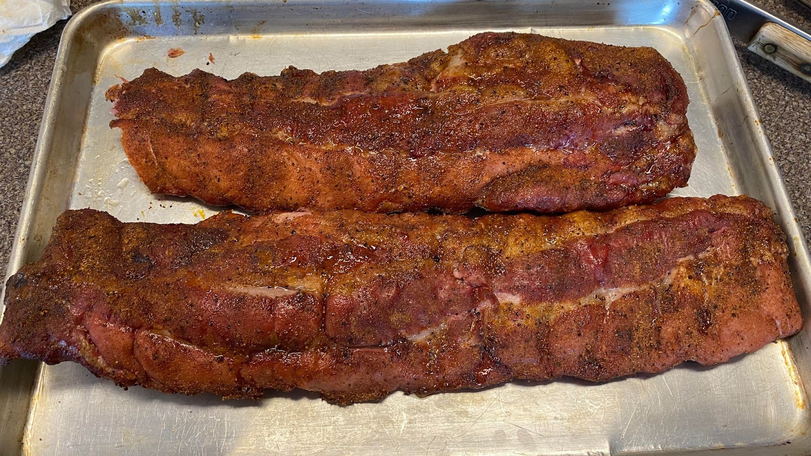Two racks of ribs pulled off the grill and on a cookie sheet