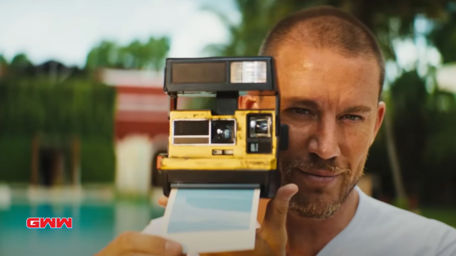 Slater holding a Polaroid camera, preparing to take a photo outside.