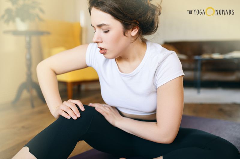 sore after yoga: woman sitting and holding her knee