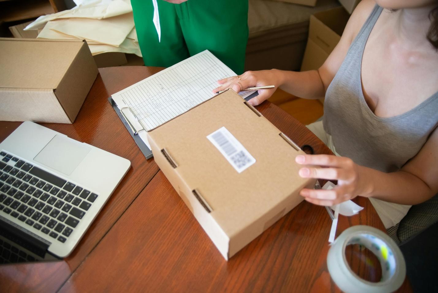 Free Woman Sitting at the Table and Packing Orders  Stock Photo