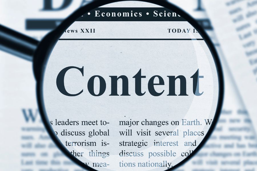 Magnifying glass highlighting the word "Content" on a newspaper.