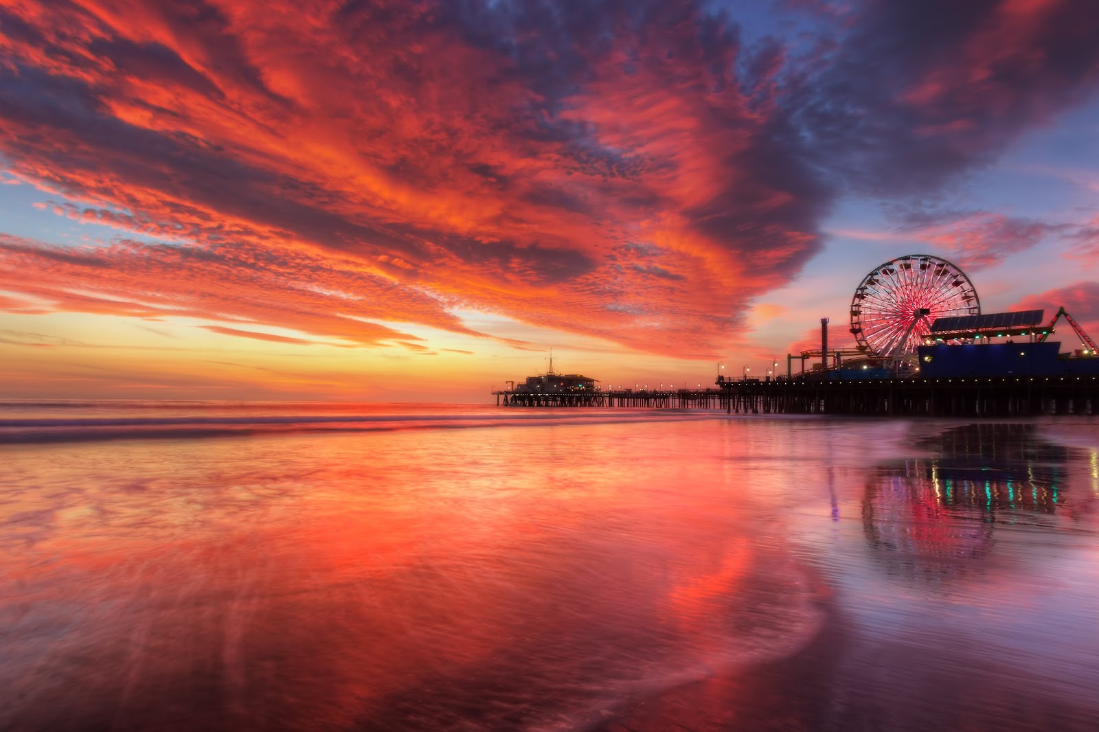 Pink sunset and a giant wheel on the seashore