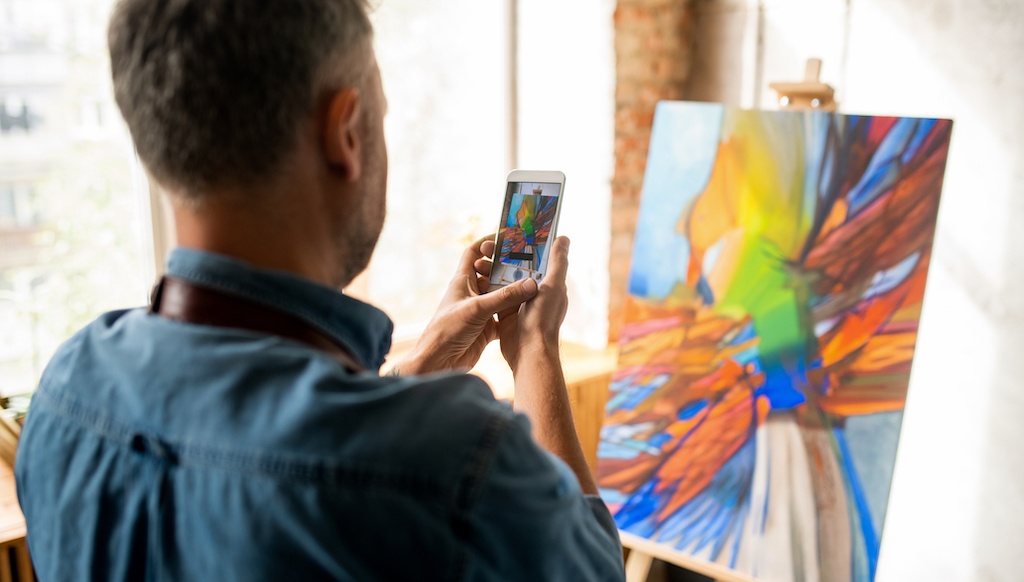 Artist photographing his artwork with a smartphone